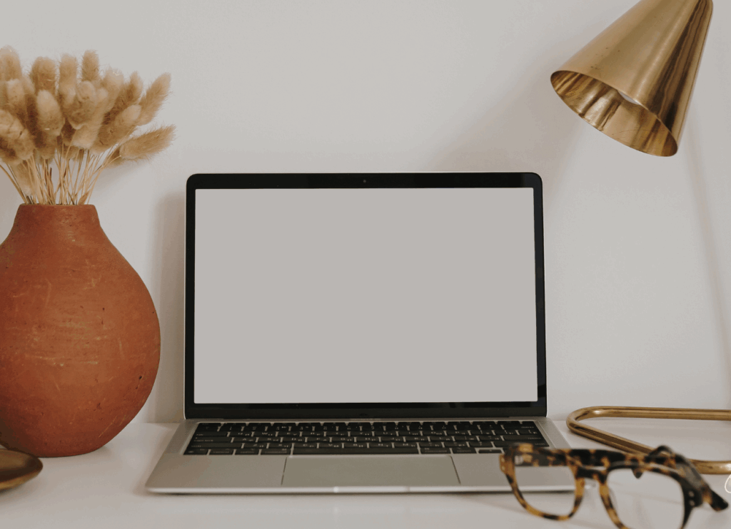 Ordinateur portable sur un bureau avec un vase et une lampe dorée